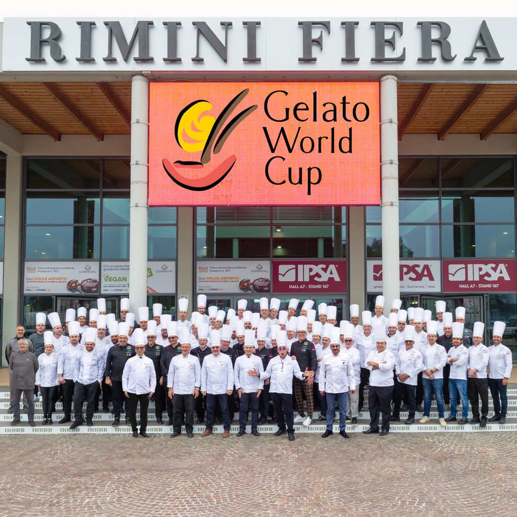 Foto di gruppo di tutti i partecipanti della Gelato World Cup 2024. Compaiono le 11 squadre, gli assistenti, i garanti,la giuria tecnica, i commissari di gara, i presidenti di giuria.